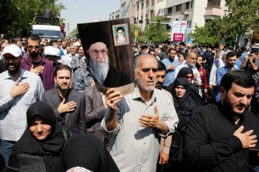 Iranians as hold poster of Iranian supreme leader Ayatollah Ali khamenie mourn during a funeral procession for 150 Iranian soldiers killed in the Iran-Iraq war (1980-1988), whose bodies were recovered from battlefields, in Tehran, Iran, on June, 27, 2019.