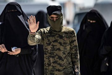 An internal security patrol member escorts women, reportedly wives of Islamic State (IS) group fighters, in the al-Hol camp in al-Hasakeh governorate in northeastern Syria, on July 23, 2019. Stabbing guards, stoning aid workers and flying the Islamic State group's black flag in plain sight: the wives and children of the 'caliphate' are sticking by the jihadists in a desperate Syrian camp. Months after the defeat of the jihadist proto-state, families of IS fighters are among 70,000 people crammed into the Kurdish-run Al-Hol camp in northeastern Syria. - TO GO WITH AFP STORY BI DELIL SULEIMAN
/ AFP / DELIL SOULEIMAN / TO GO WITH AFP STORY BI DELIL SULEIMAN