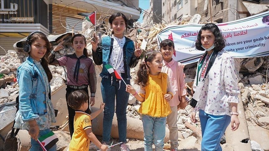 Des enfants palestiniens qui posent devant leurs domiciles bombardés par l'occupation.