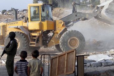 Un bulldozer de l'armée israélienne détruit les maisons palestiniennes et un centre communautaire dans le village d’Umm Al-Kheir, dans le sud de la Cisjordanie, près de la colonie israélienne de Karmel, le 24 août 2016. ©AFP