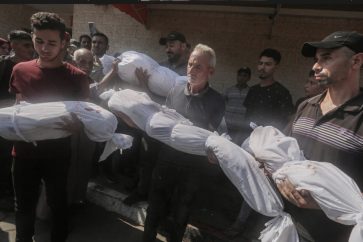 Des Palestiniens tenant des corps enveloppés à l'hôpital Al-Aqsa de Deir al-Balah, à Gaza, le 10 juillet 2024. ©apa Images