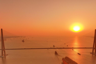 Cette photo prise par un drone le 9 décembre 2024 montre le «NGUYA FLNG», une installation flottante de gaz naturel liquéfié, en train d'être remorqué sur le pont Sutong (Suzhou-Nantong) qui traverse le fleuve Yangtze dans la province de Jiangsu, dans l'est de la Chine.